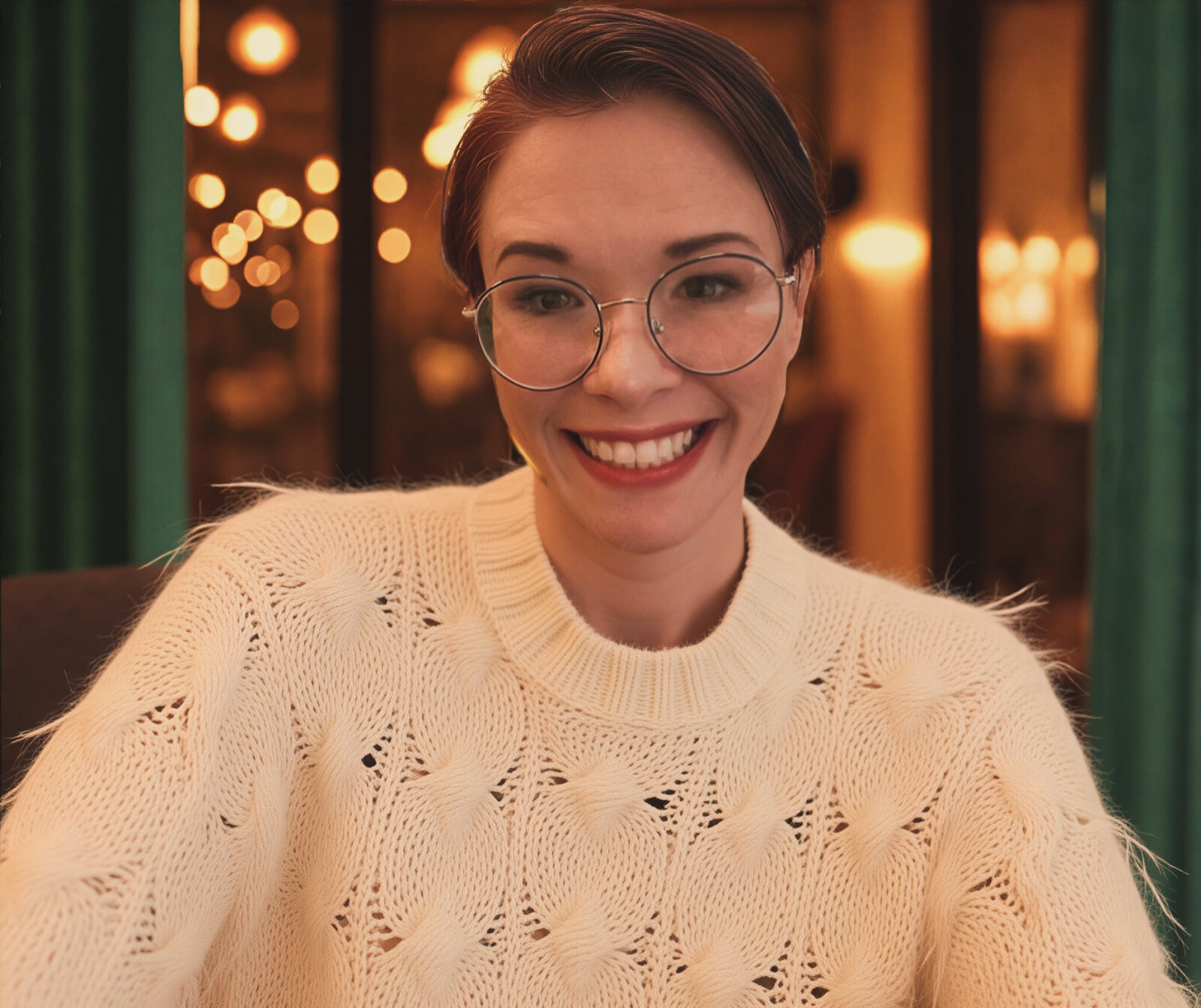 Ashley Jelliffe smiling in a cream sweater and round glasses
